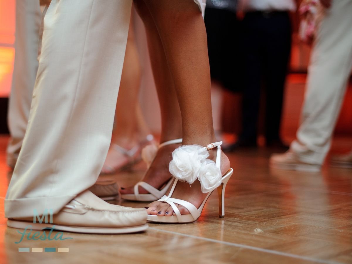 Close-up of a couple dancing on a wooden floor, wearing elegant white wedding dance shoes.