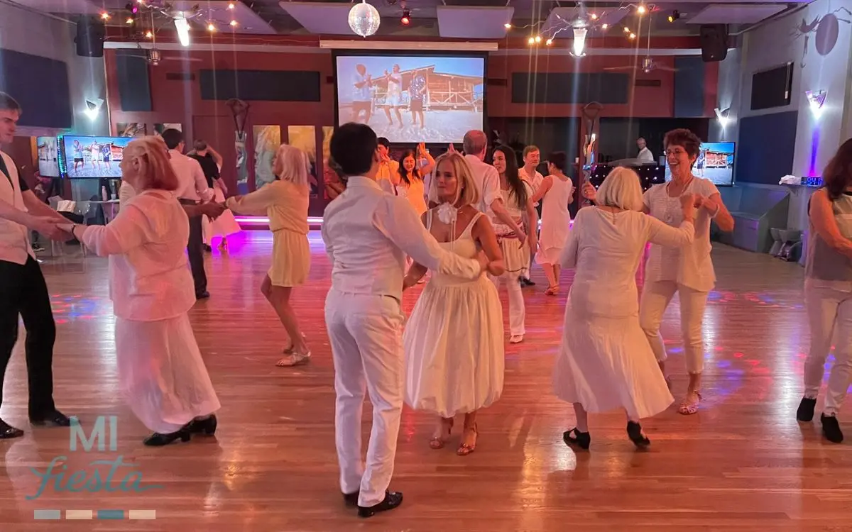Dancers celebrating the white party at TK Dance Studio in all-white outfits on the ballroom floor