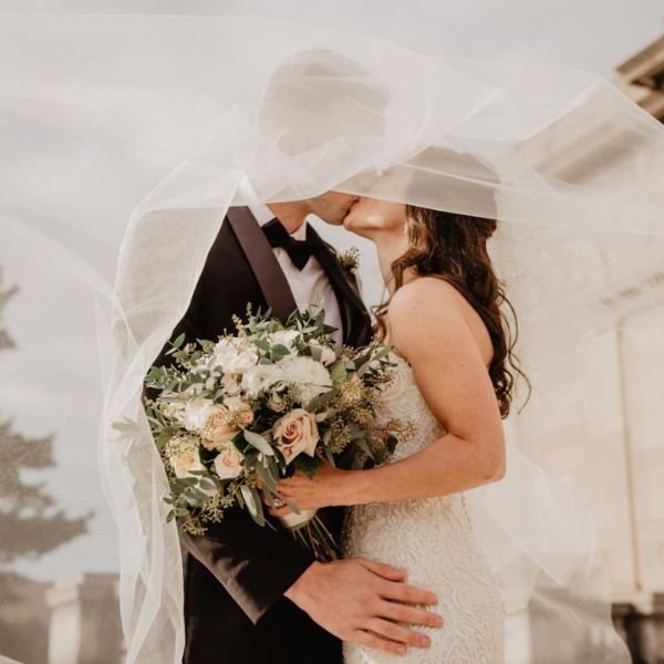Bride and groom sharing an intimate moment under a flowing veil on their wedding day